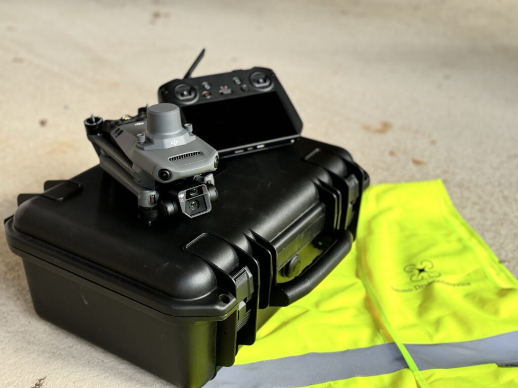 dji drohne und bediengerät liegen auf dem koffer. Auf dem Boden ist eine Warnweste von Immo-Drohnenservice aus NRW zu sehen