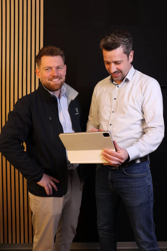 Die beiden Gesellschafter Fabian Tittgen und Rico Kossik schauen sich Ergebnisse einer Drohnendienstleistung auf dem Tablet an