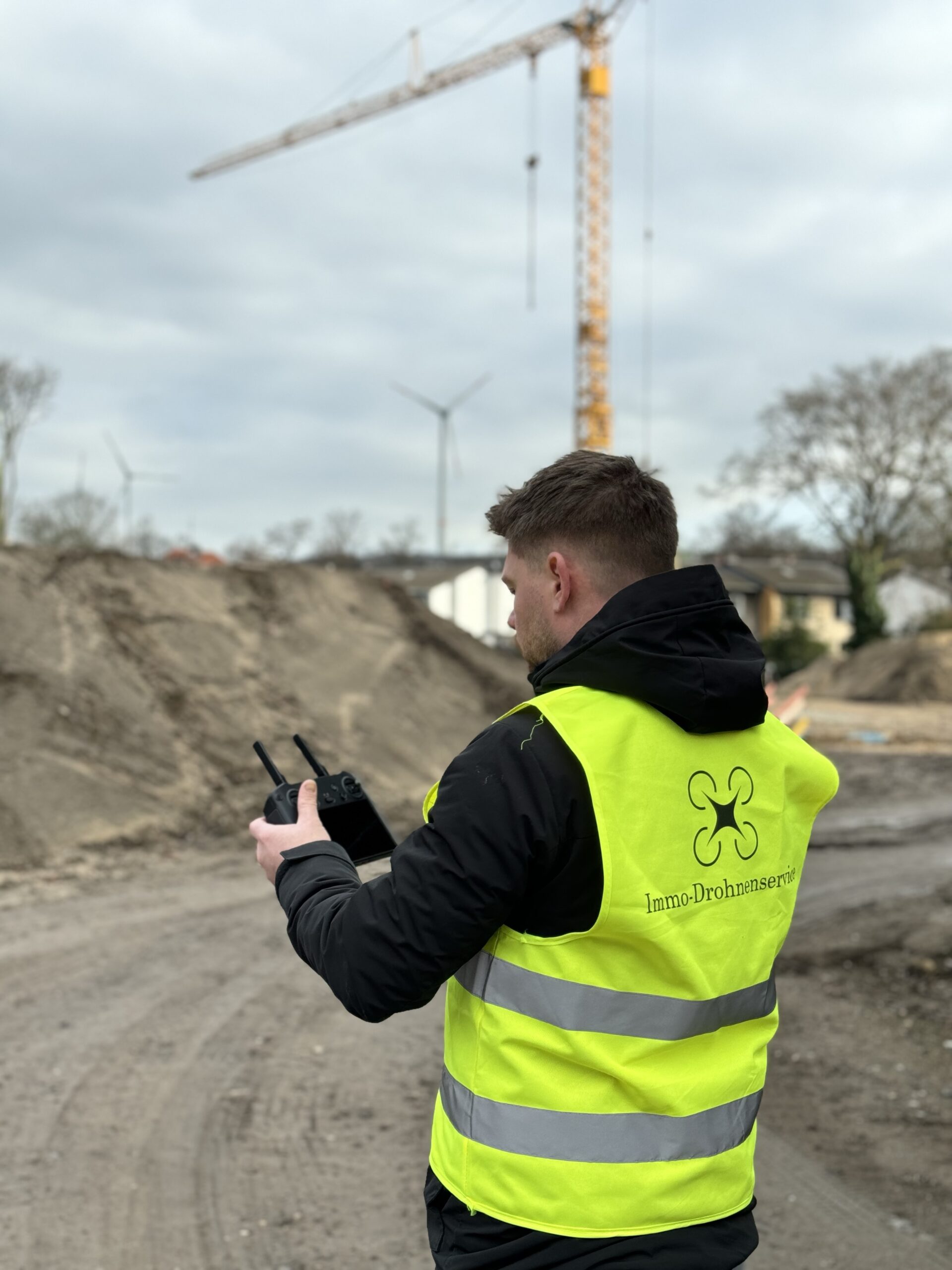 Drohnenpilot von Immo-Drohnenservice steuert die Drohne auf einer Baustelle