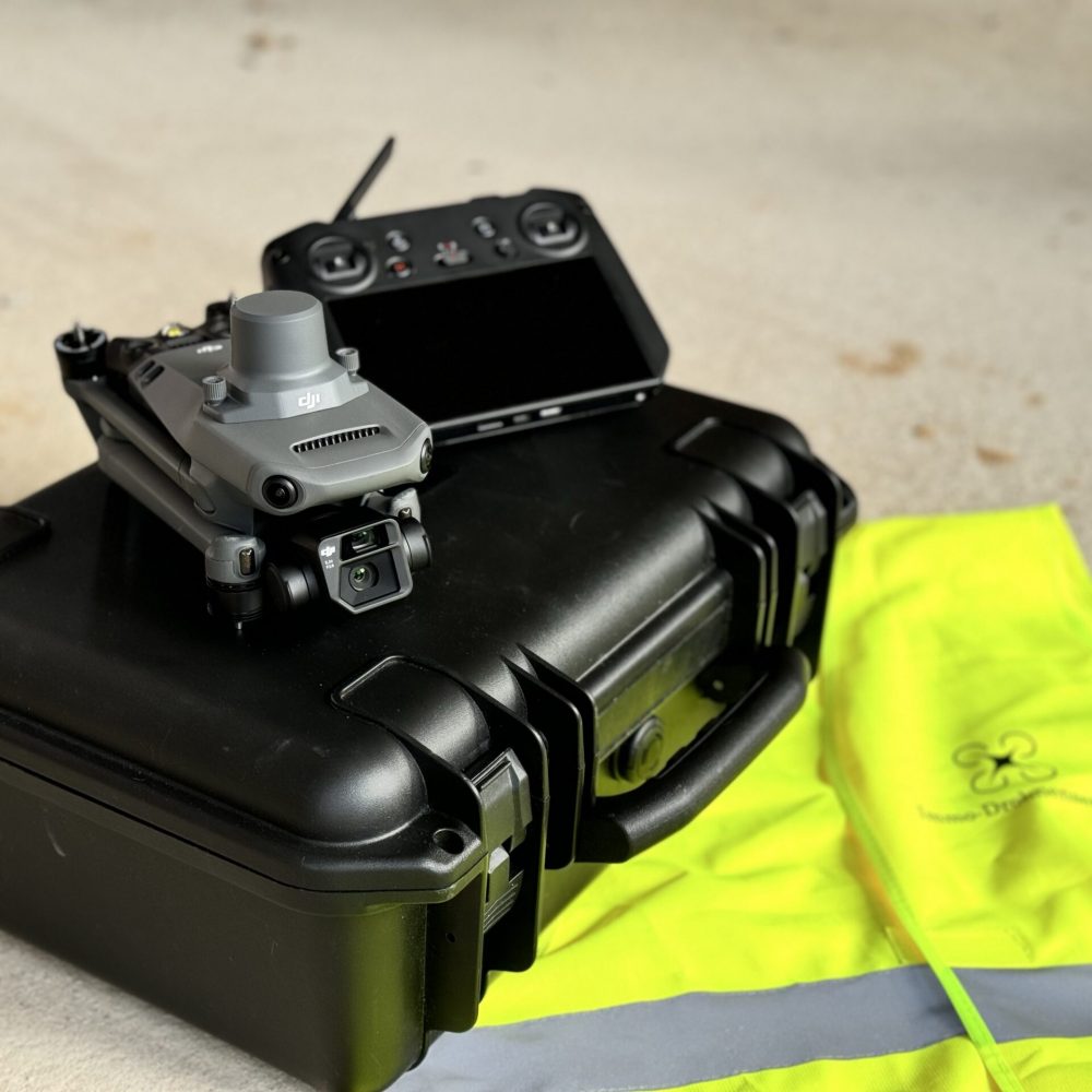 dji drohne und bediengerät liegen auf dem koffer. Auf dem Boden ist eine Warnweste von Immo-Drohnenservice aus NRW zu sehen